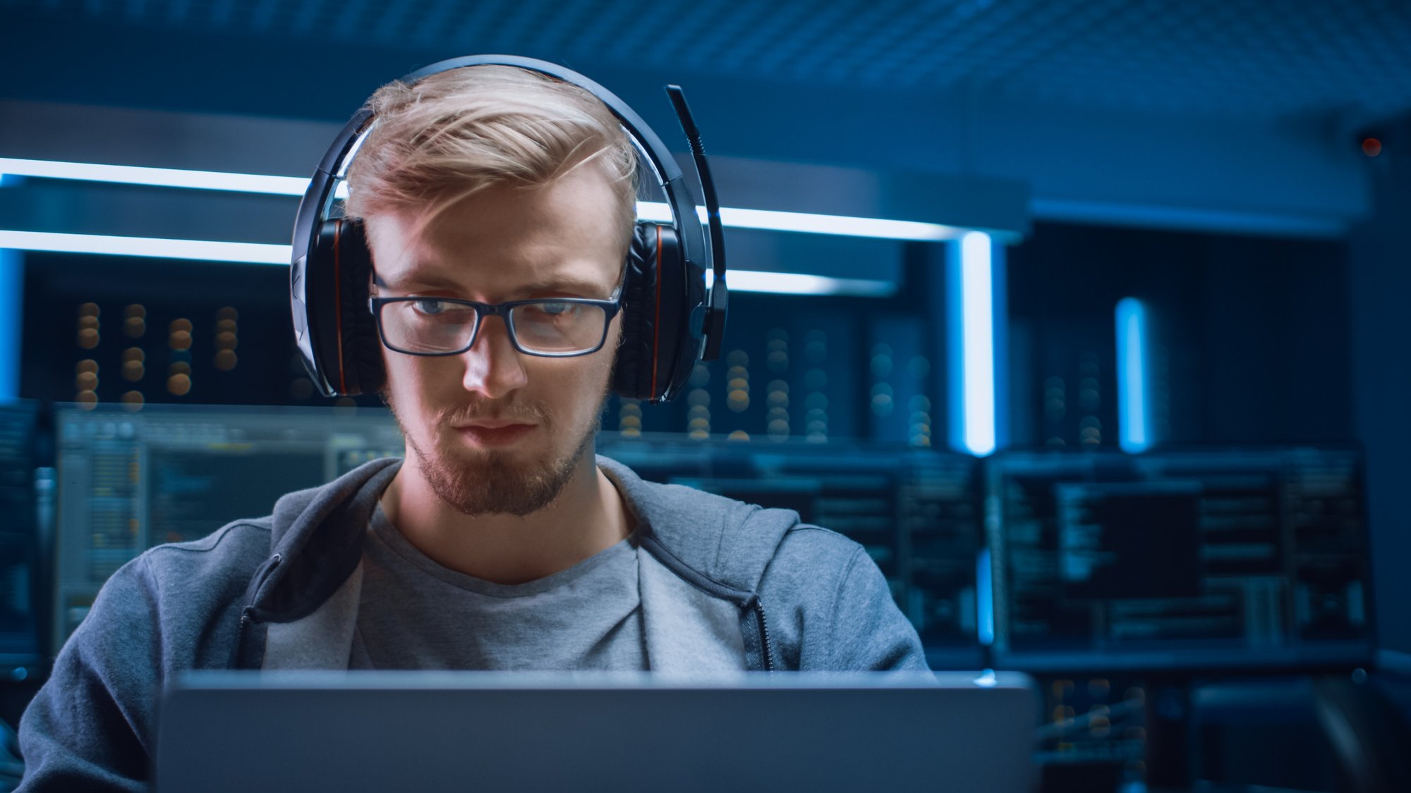 portrait-d-un-developpeur-de-logiciels-un-hacker-un-joueur-portant-des-lunettes-et-un-casque-assis-a-son-bureau-et-travaillant-jouant-sur-un-ordinateur-portable-a-l-arriere-plan-un-environnement-de-haute-technol